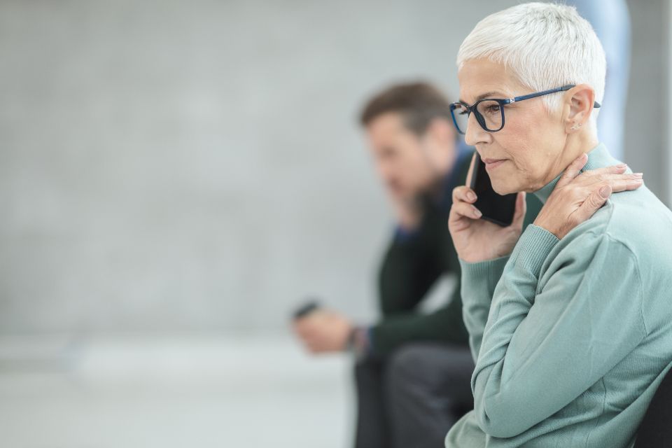 A smiling grandmother with glasses talking on her phone at home