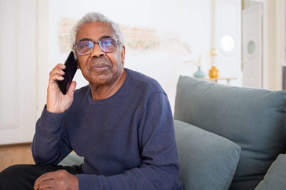 An older man on his sofa at home, talking on his phone